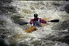 White water kayaker powers through the foamy rapids.
